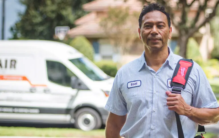 A Del-Air electrician standing outside, with a service van in the background