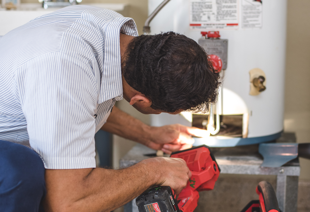 A plumber servicing a water heater