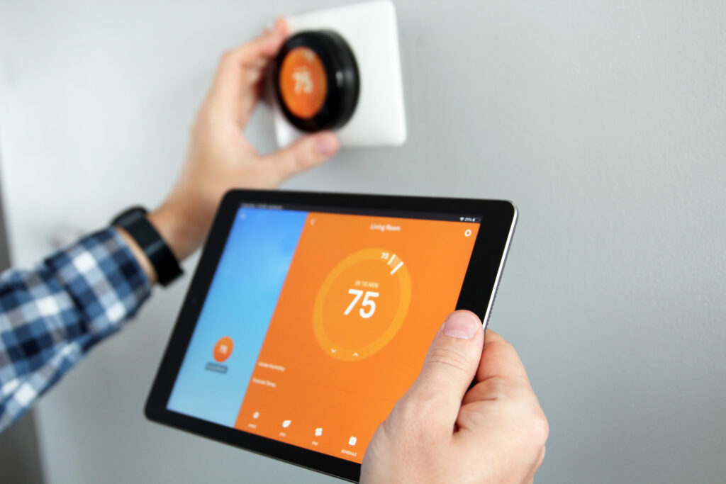 Person is adjusting temperature using a tablet with smart home app in modern living room