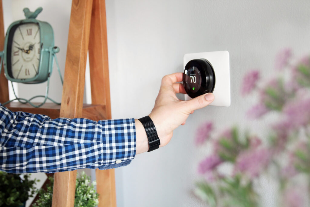 Person adjusting temperature on a thermostat in the living room.