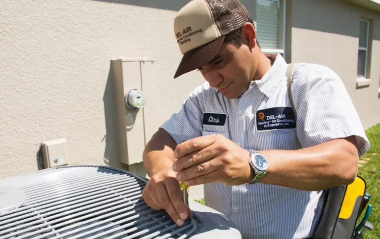 Del-Air technician performing repairs on an outdoor HVAC unit