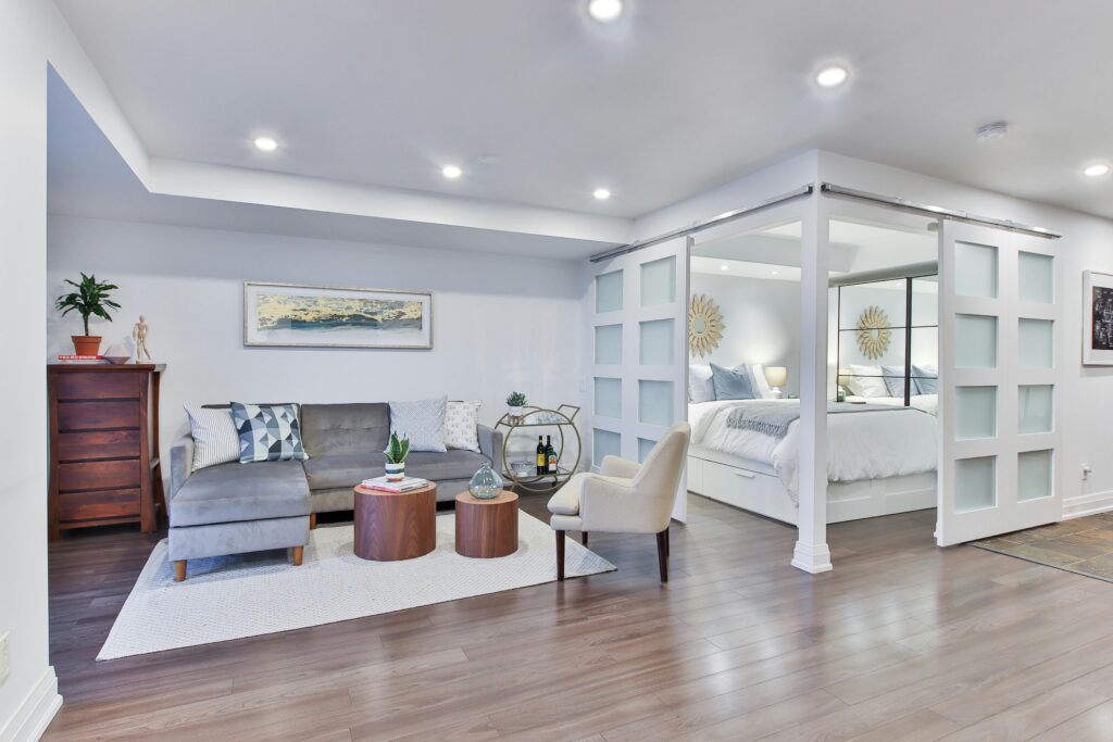 A modern master bedroom and seating area with recessed lighting throughout.