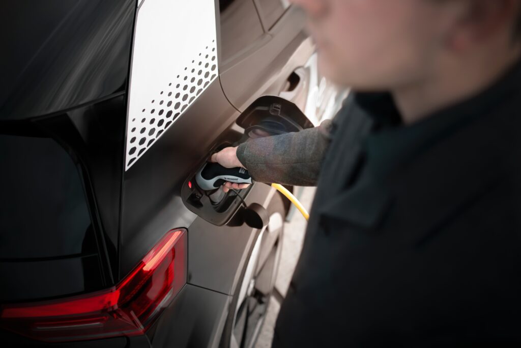 man charging electric vehicle at home