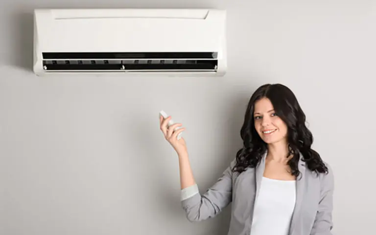 A homeowner is standing next to a wall-mounted ductless mini-split HVAC unit