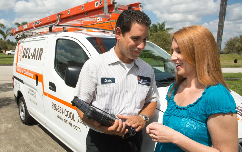 Del-Air technician standing next to a client in front of a Del-Air service van