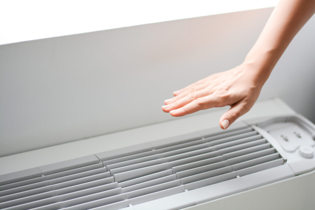 Hand over a ductless HVAC system, checking the temperature