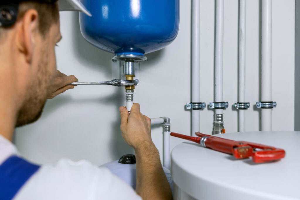 plumber installing expansion tank for house heating system.