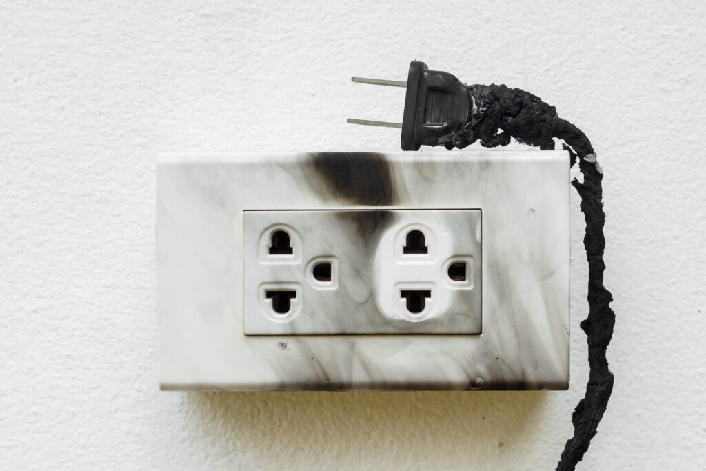 A burned electrical plug with a scorched outlet.