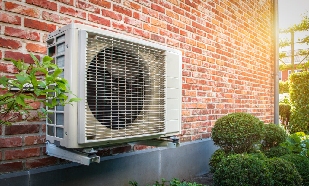 Outdoor heat pump unit beside a brick home