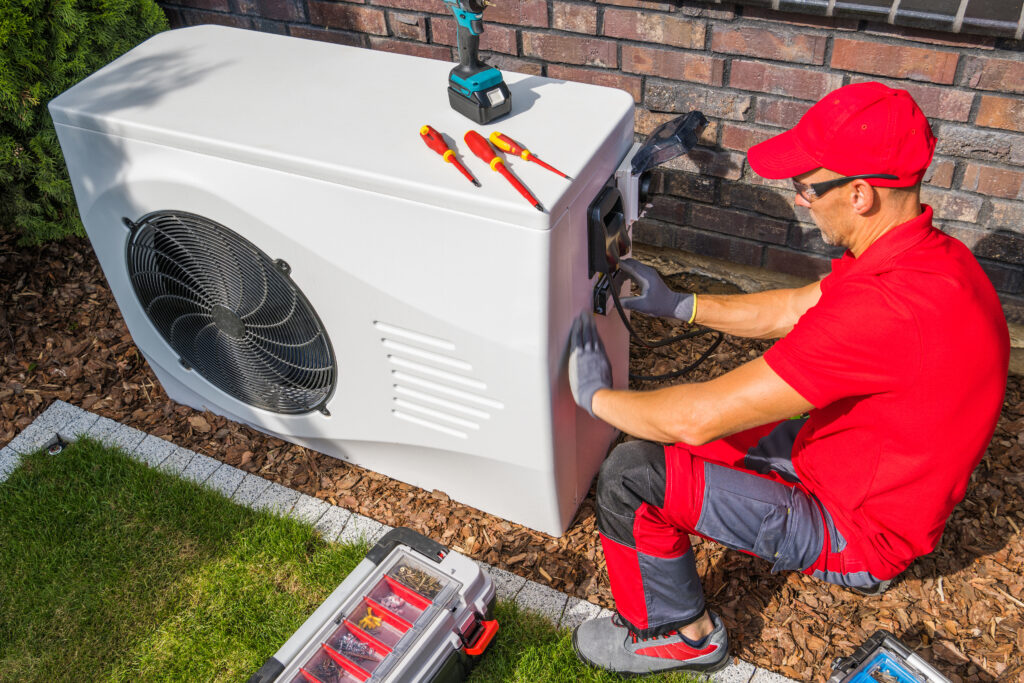 A technician working on an outdoor heat pump unit