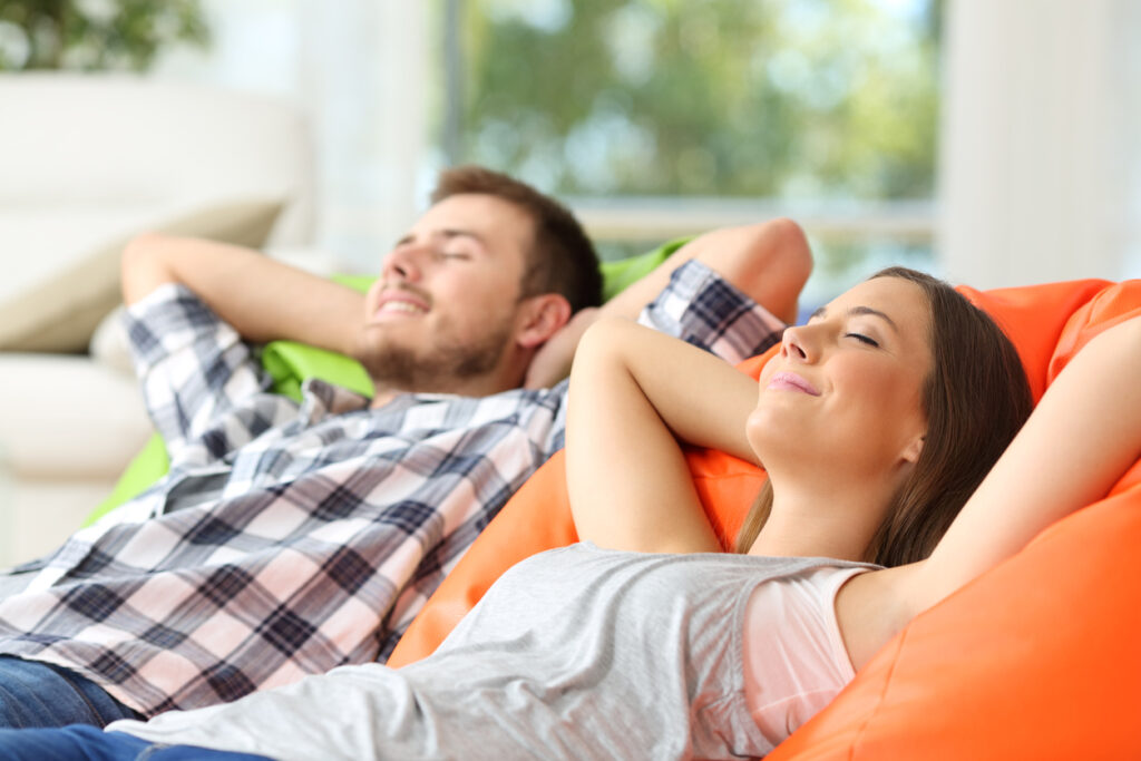 Couple relaxing lying on comfortable poufs in the living room at home