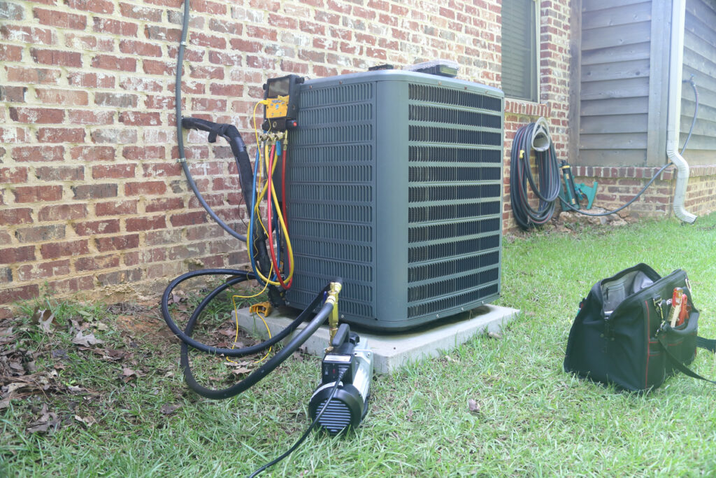 Gauges and vacuum pump surrounding an outdoor HVAC unit.